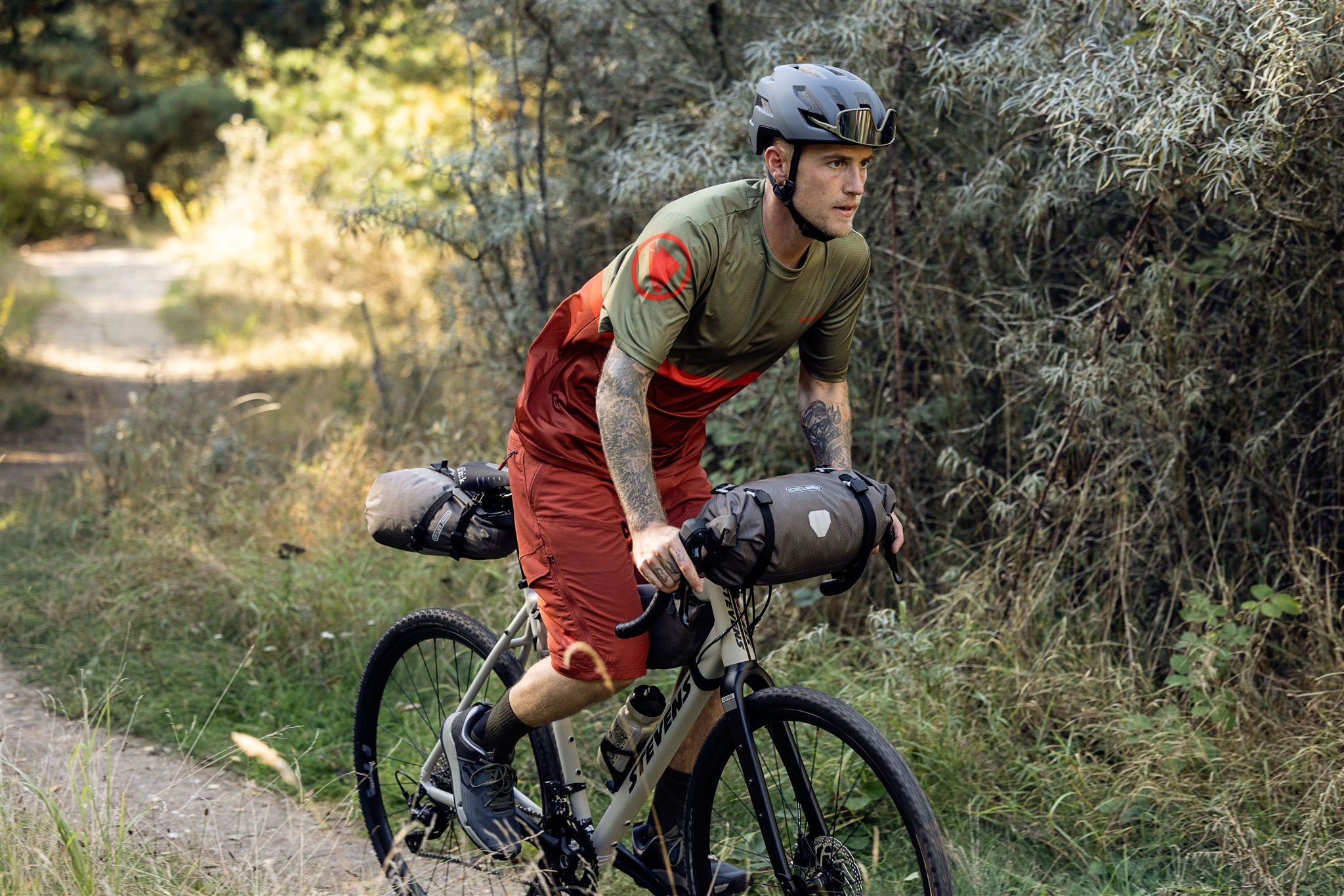 Radfahrer befestigt ORTLIEB Handlebar-Pack Flex in dark-sand am Lenker im Gelände